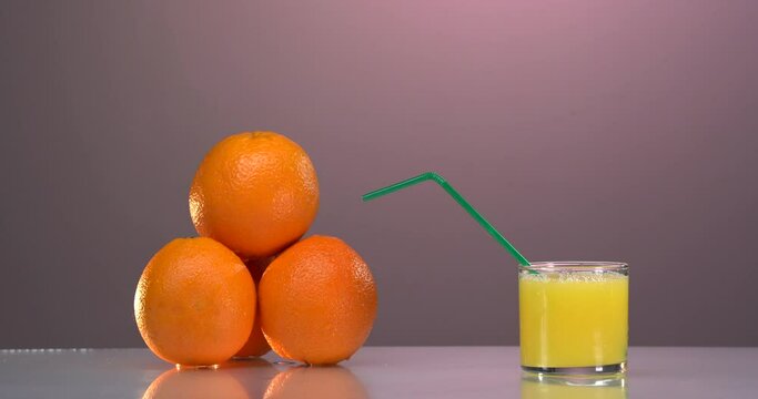 Man's hand puts orange slice and straw into glass with orange juice. Close up