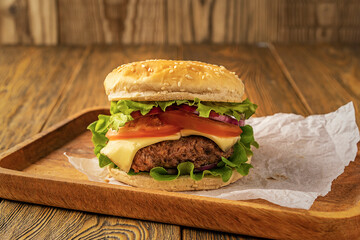 Homemade delicious hamburger on a wooden table, rustic style. Fast food. Space for the text.