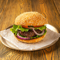 Homemade delicious hamburger on a wooden table, rustic style. Fast food. Space for the text.