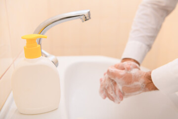 hand washing with soap or gel under running water in the washbasin, cleanliness and hygiene, men's...