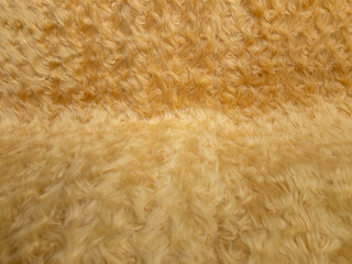 Gold animal wool texture background. Close-up texture of plush fluffy fur rug for product backdrop, straight view