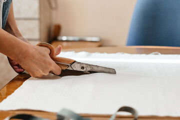 A needlewoman cuts fabric, a measuring tape for needlework, cutting and sewing with scissors