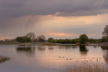 Sunset views over a reservoir, moody cloudy skies with vibrant colours and reflections in the water