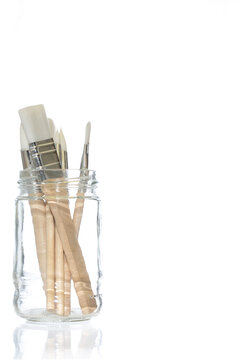 a set of painbrushes in a glass jar shot on a white background