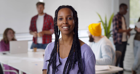 Successful businesswoman standing in creative office and looking at camera while smiling