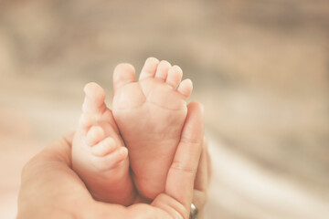 Obraz na płótnie Canvas Mother holding newborn feet in her hand. Close- up. Creamy velvet adjustment.