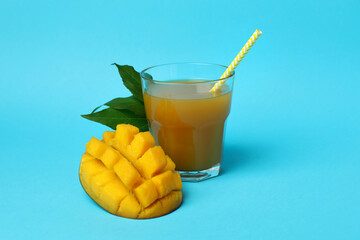 Ripe mango fruit and juice on blue background