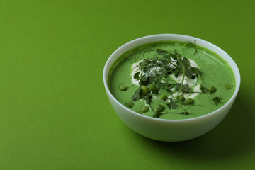 Bowl of pea soup on green background
