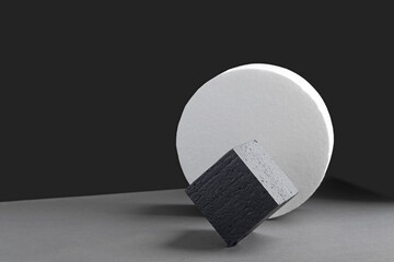 Concept of 3-d podium made of geometric shapes. White circle and black square standing on its edge,...