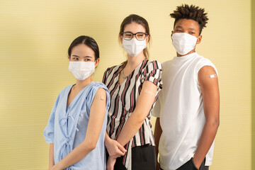 A group of young, multinational Asian, white women and African American men vaccinating their plastered arms feel safe from contracting COVID-19. 