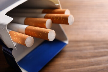 Pack of cigarettes on wooden table, closeup