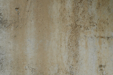 The uneven surface of an old concrete wall with splashes of crushed stone .