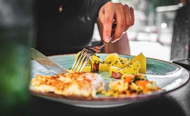 woman hand holding fork and knife eat chicken breast meat with potato in a plate