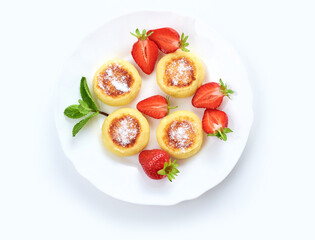 Cottage cheese pancakes, syrniki, ricotta fritters on ceramic plate with fresh strawberry.