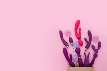 A paper shopping bag filled pink Purple silicone sex toys on a white background. Erotic toy for...