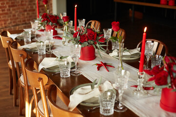 Unusual decoration of a wedding table with red roses, eucalyptus in red boxes with red candles and chili peppers in a dark interior