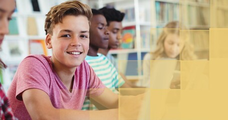 Composition of smiling schoolboy in class, with yellow block copy space on right