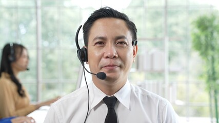 Portrait of smart man using headset to talk with customers via internet working on customer service...