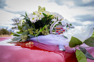 Wedding bouquet and rings on an American car.
