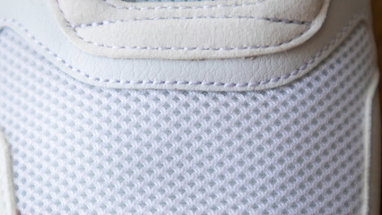 White color mesh fabric on a part of sports shoes. Running shoe net. Sportswear textured lattice. Textile texture background. Detail of a white sneaker in fabric with laces. Fragment of sports shoes.