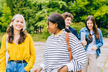 Multi-ethnic group of college students walking together in university campus. Education and friendship concept.