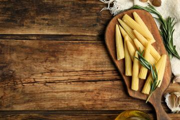 Fresh baby corn cobs on wooden table, flat lay. Space for text