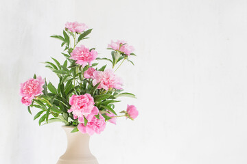 pink peony in ceramic vase on background old wall