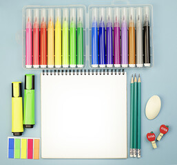Obraz premium Stationery school supplies on a blue bright background with a notebook in the center, colored markers and pencils. Back to school. School learning concept. Copy space.