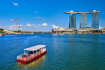 Tourist cruise boat navigating in Marina Bay, Singapore. iconic Marina Bay Sands, Shoppes mall, ArtScience museum, Helix bridge and Singapore Flyer. 