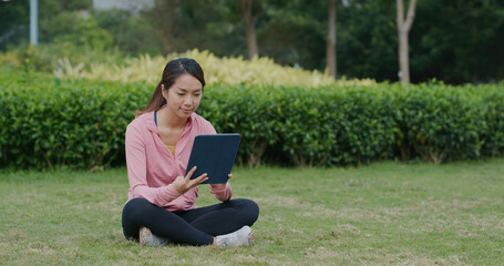 Naklejka na ściany i meble Woman use of tablet computer at park