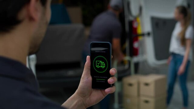 Rear view of delivery man holding phone with mobile app. Shot with RED helium camera in 8K.