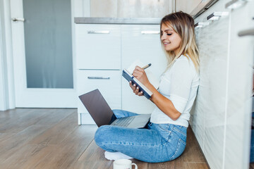 Business woman drinking a cup of coffee and using her laptop for working in one bright morning. Home work concept.