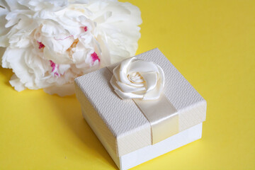 White peony flower and white gift box on yellow background