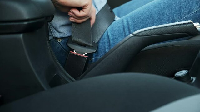 Woman hand fastening seat belt in car, safety driving