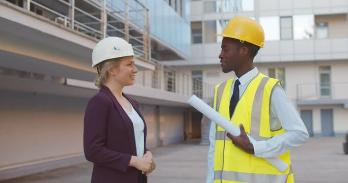 Diverse contractor and architect shaking hands outside construction site