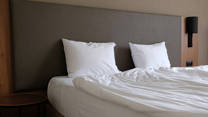 Close-up fragment of bedroom with empty bedside table, reading lamp and a USB socket in modern interior​ design home or hotel. Soft pillow and blanket, stylish comfortable furniture.