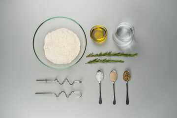 Knolling Photography - Rosemary Focaccia Bread Recipe. Top view of all the ingredients of focaccia and topped with fresh rosemary, olive oil, and flaky sea salt.
