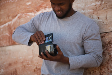 African american man in a gray t-shirt trying to insert a cassette tape into a 1980s walkman.