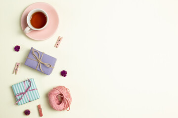 Gift boxes, cup of black tea, pink string, wooden clip, dry flowers on yellow green background. flat lay, top view, copy space