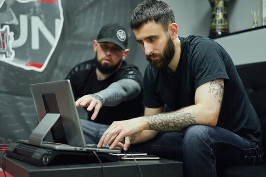 Male coworkers working on computer in tattoo salon