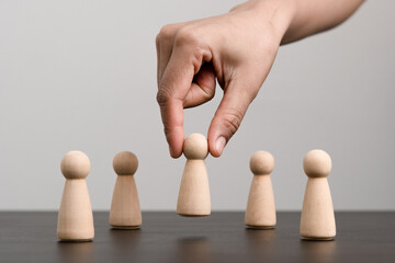 Human resource, Talent management, Recruitment employee, Successful business team leader concept. Hand chooses a wooden people standing out from the crowd.