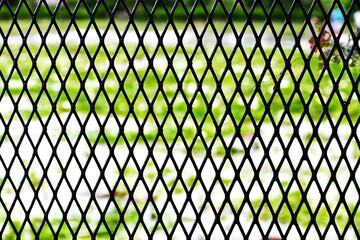 Fototapeta premium The surface of black plastic mesh and defocused nature background 