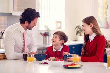Obraz na płótnie Canvas Father Wearing Suit Having Breakfast With Children In School Uniform Before Work