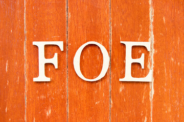 Alphabet letter in word foe on old red color wood plate background
