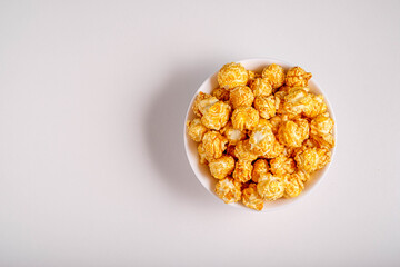 Popcorn with caramel flavor in a white plate on a white background