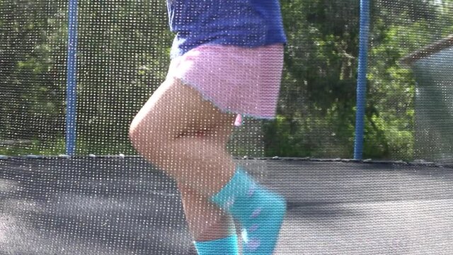 a Little child girl jumping on the trampoline in the back yard