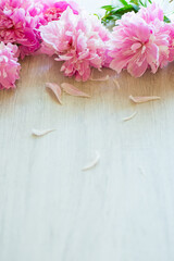 several branches of blooming pink peonies on a wooden table
