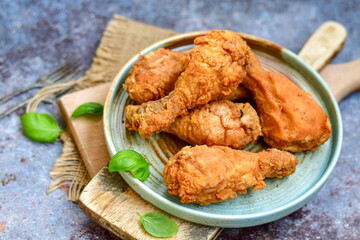 
 Crispy  deep fried home made    chicken   legs Breaded  with  almond flour chicken  breast fillets  with chilly peppers and fresh   basil on wooden rustic background. Ketogenic diet food