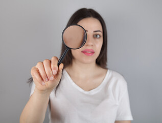  Young woman looks through a magnifying glass.