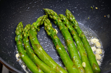 asparagus with garlic fried in a pan close-up